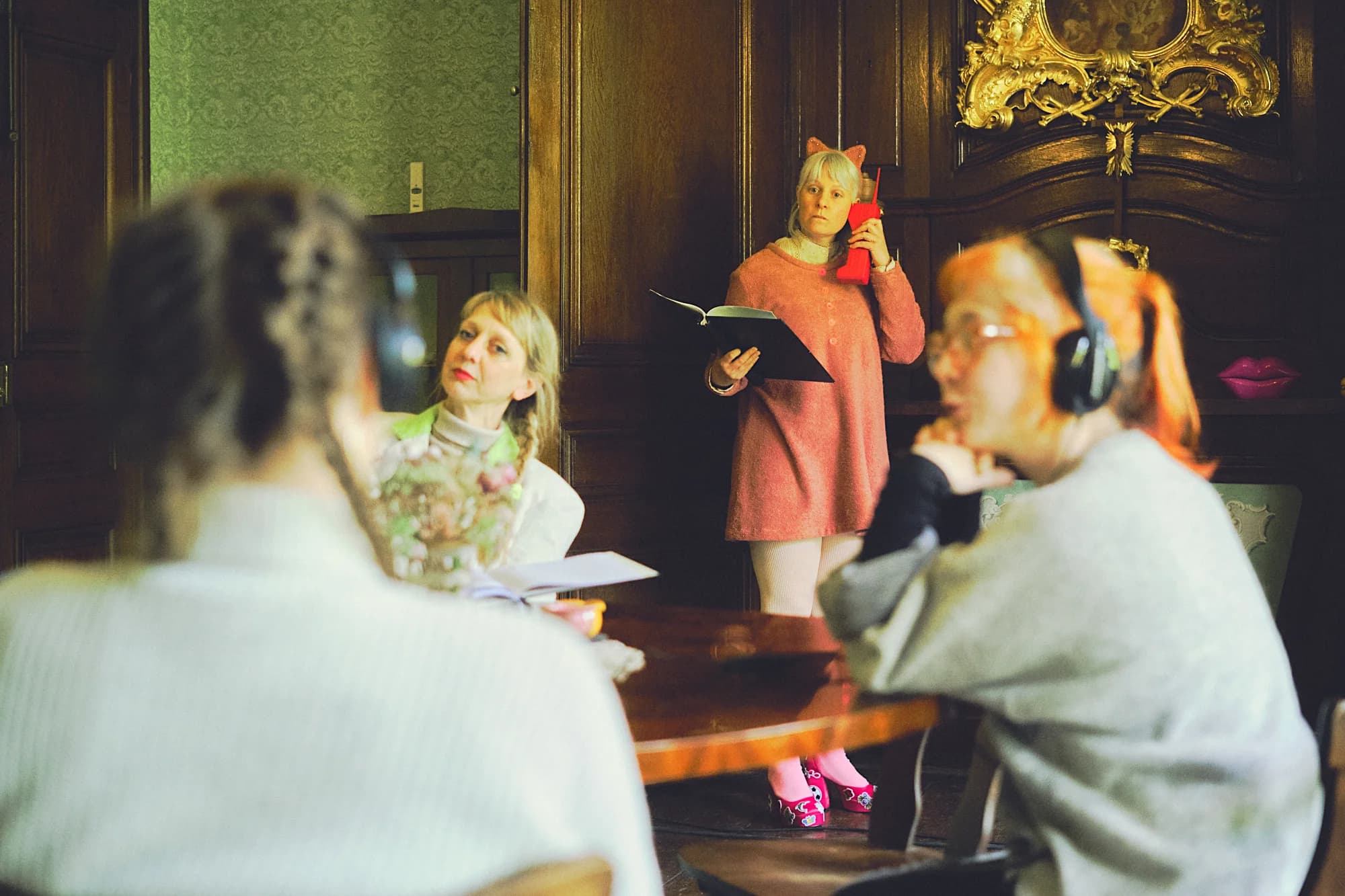 4 Personen an einem Tisch, teils mit Kopfhöhrern lesen einen Text.